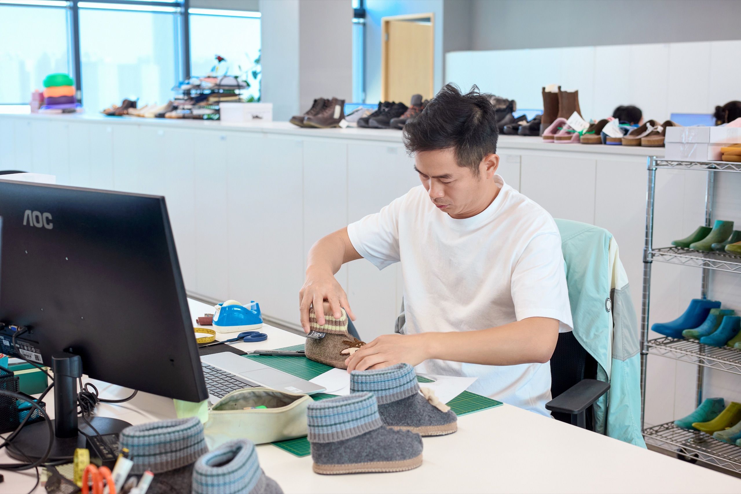 Mitarbeiter prüft einen Schuh an einem Arbeitstisch